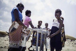 Teresa Jone Vilanculos (right), 14, filling her bottle at the tap stand. She has fled her village Mangalaforte, together with her family, when their house was washed away in cyclone Idai. (Photo: Micas Mondlane / Oxfam Novib)