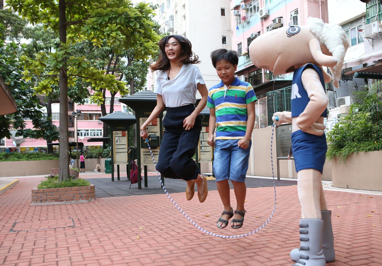 香港女子跳高代表楊文蔚和「公平咩」、杰仔一起到公園裏跳繩。(丁世威/樂施會)