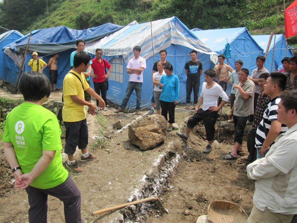乐施会在宝兴县灵关镇安坪村一个安置点，开展环境卫生设施项目，图为技术人员向村民解释环保厕所的原理。