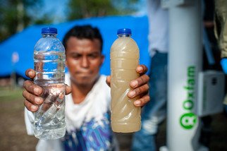 有灾民展示经由乐施会净水器处理后的食水，与未经净化的食水比较，有明显的分别。（图片：Hariandi Hafid／乐施会）