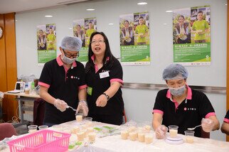 澳門永亨銀行義工服務隊總幹事劉少美女士(中)簡介澳門永亨銀行義工隊即場示範樂施米的包裝流程，包括量米、分米和包米。