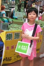  在香港，義工協助義賣樂施米，為四川地震籌款賑災。這女孩和父母在銅鑼灣參與此活動