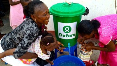 两位妇女从乐施会的公共衞生教育中学习如何预防伊波拉病毒后，再教导他们的孩子洗手。（拍摄：乐施会）