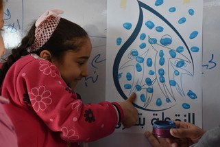 樂施會在2017年為敘利亞首都大馬士革65所學校超過一萬三千名學生提供衛生教育活動。10歲的Ramia在完成樂施會的衛生教育工作坊後，在印有水點圖案的海報上打手印，承諾會時刻保持個人清潔和珍惜用水。（攝影︰Dania Kareh / 樂施會）