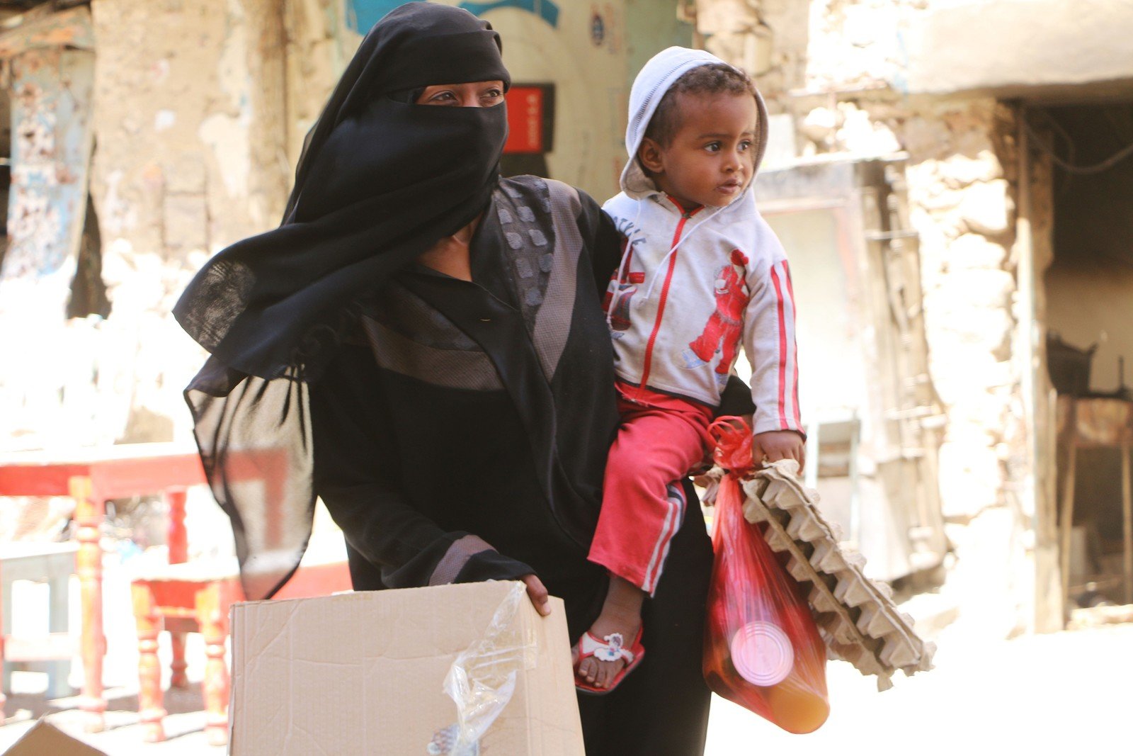 Umm Ayman from the city of Taiz carries her child Ayman as she searches Taiz’s cafes and restaurants for leftovers to feed her children. People in Taiz city, in the front line of the conflict, told Oxfam in February that there were no vegetables or infant formula milk available in the market, and reported that in some areas, food prices have increased by 200 per cent. Many said that they eat only one meal per day to leave enough food for their children. Some said they went without food for 36 hours during times of intense conflict.