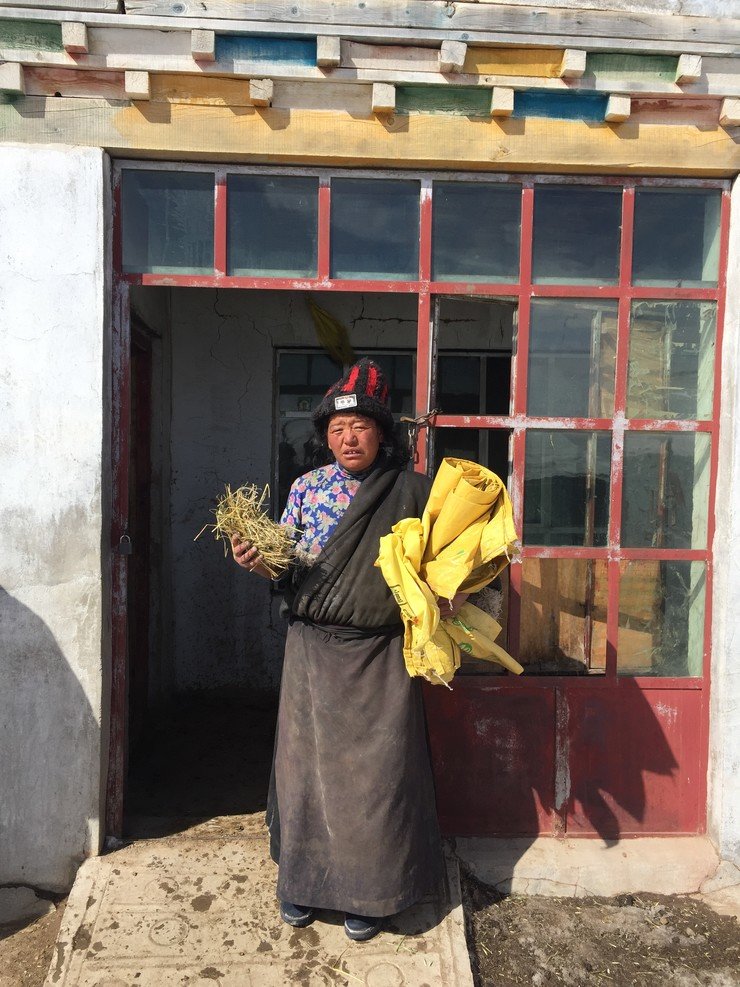 Ai Da holding some of her yak’s feed and poly woven bags to keep them warm. The snowstorm killed 44 out of 57 of her yaks, which badly affected her livelihood.