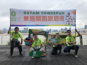 Four people holding a banner that says Oxfam TowerRun as well as some event-related props.