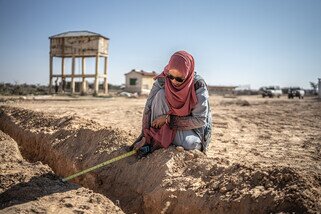 Woman measuring a tunnel in the ground with a measuring tape.