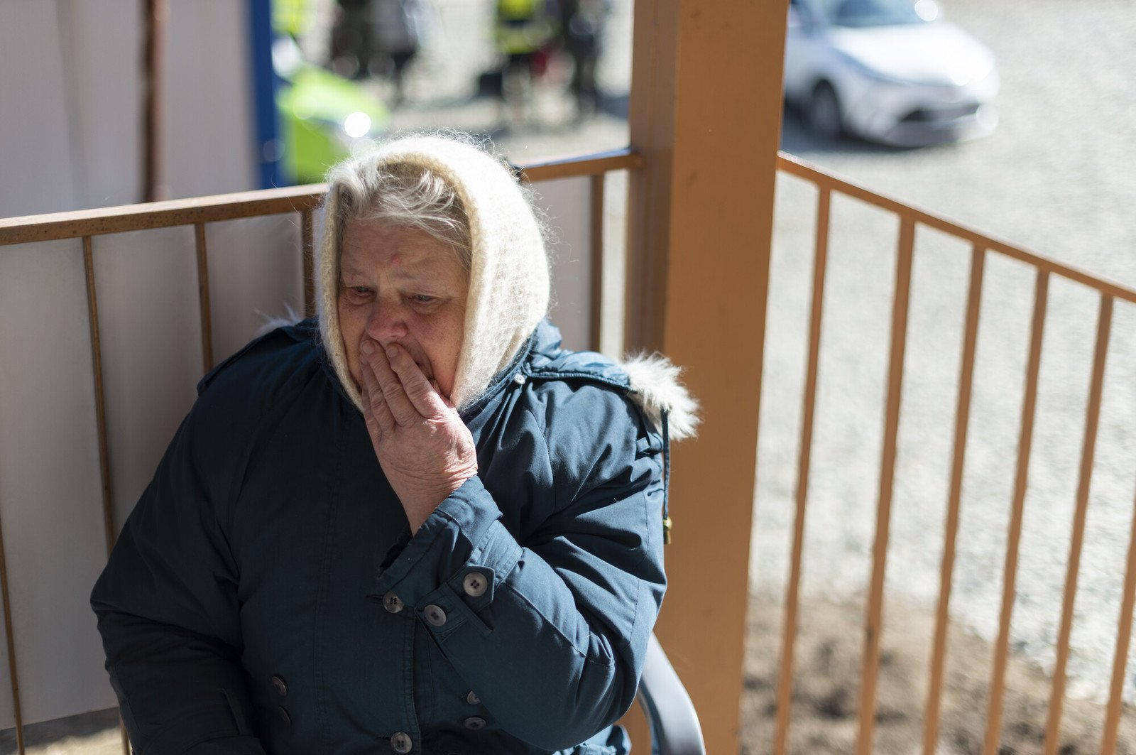 Grandma sitting on a porch with her hand over her mouth.
