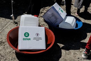 Boxes with hygiene items and jar in a shallow bucket.