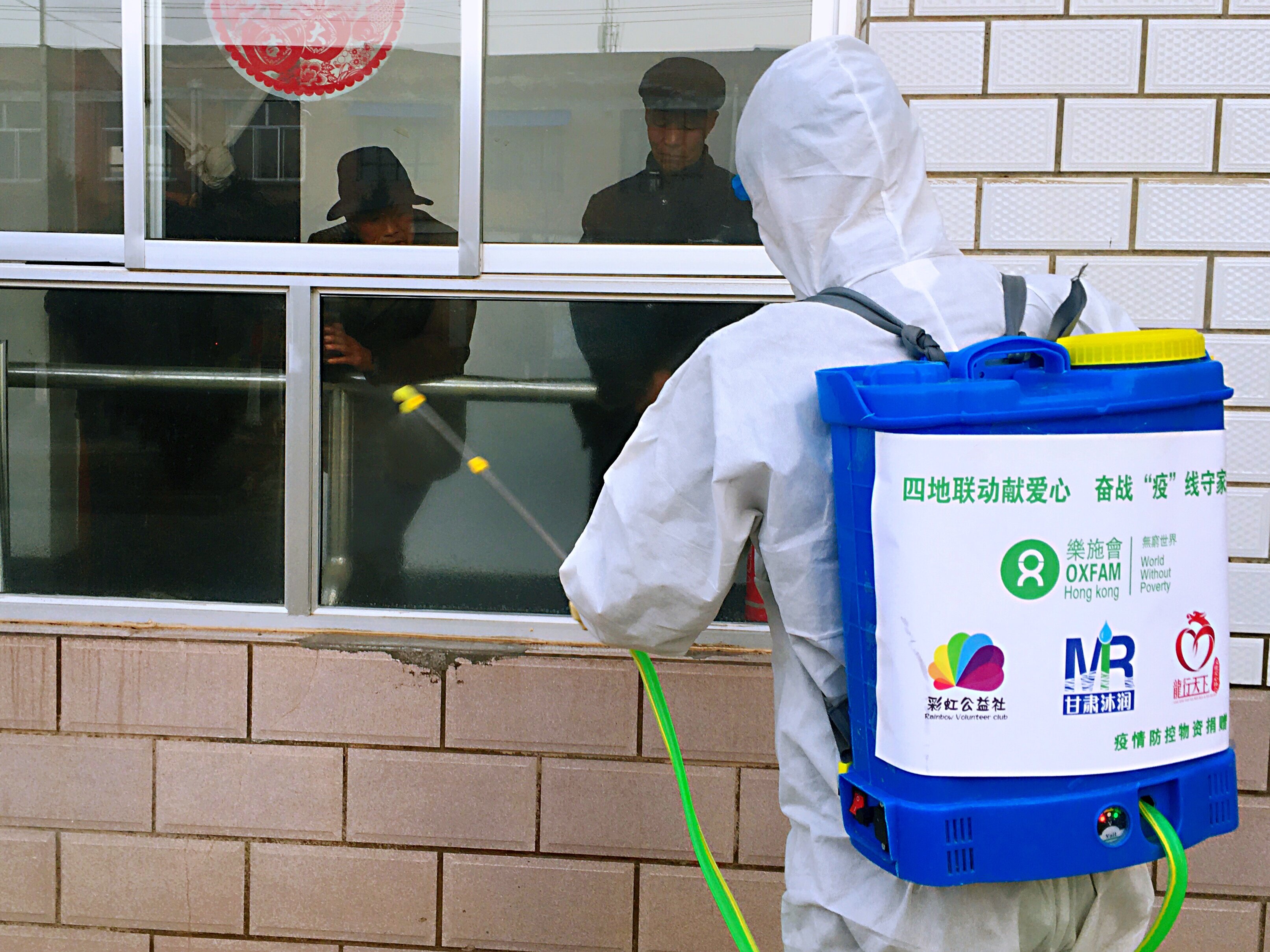 Person in protective gear disinfecting a building.