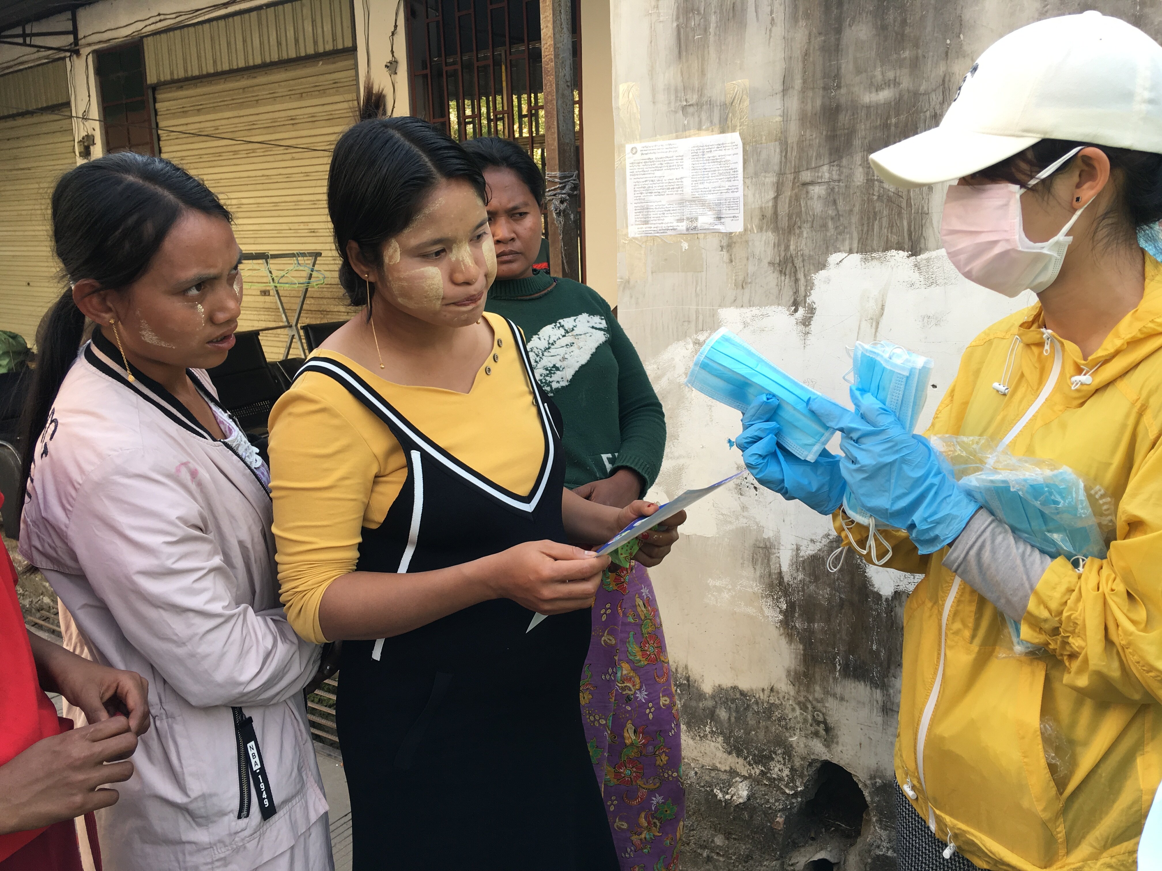 Staff handing out relief items and recipients reading a leaflet.