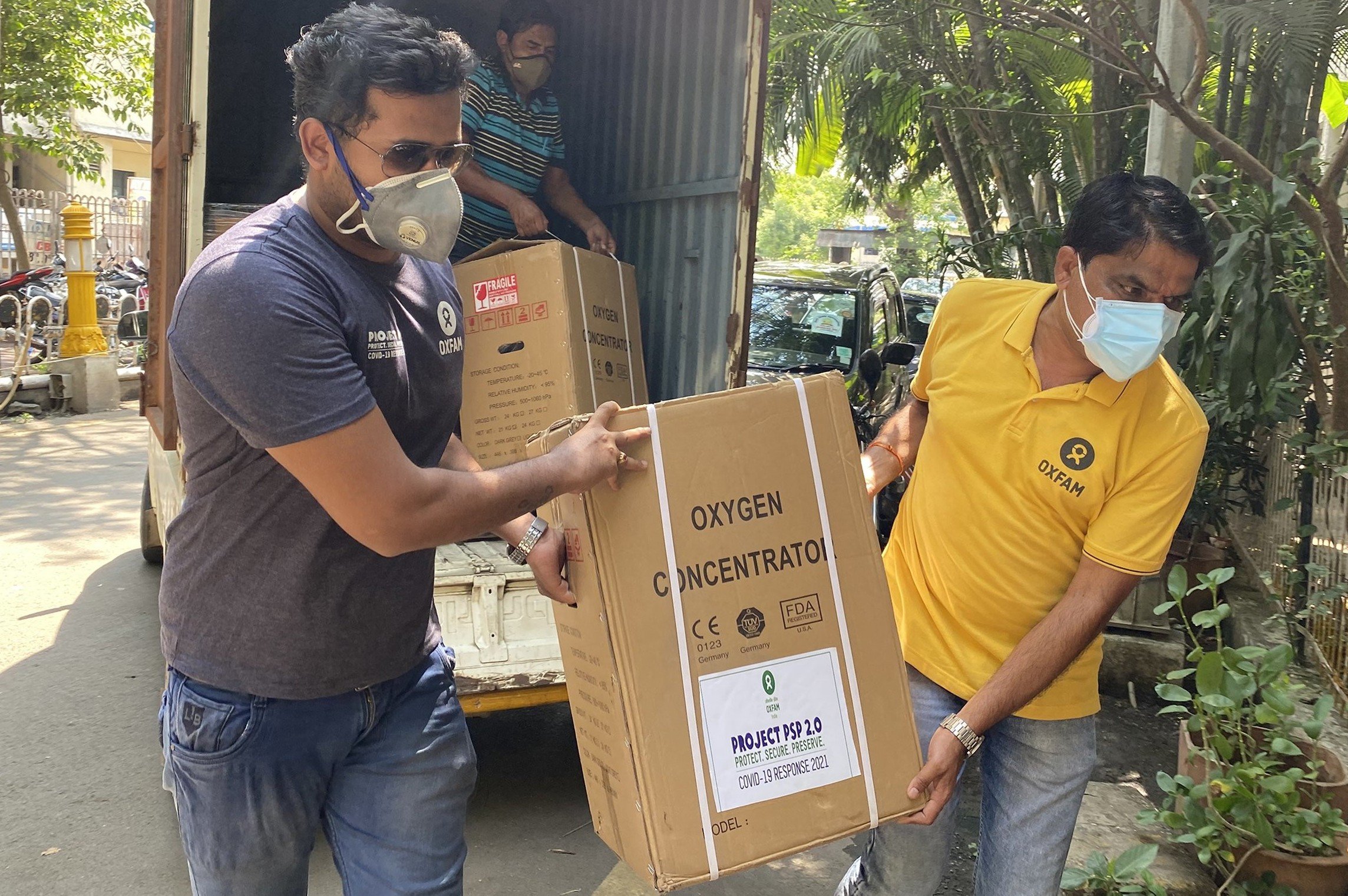 Oxfam staff Nikhil Wagh and Parmeshwar Patil carrying an oxygen concentrator into the Yashwantrao Chavan Memorial Hospital. 